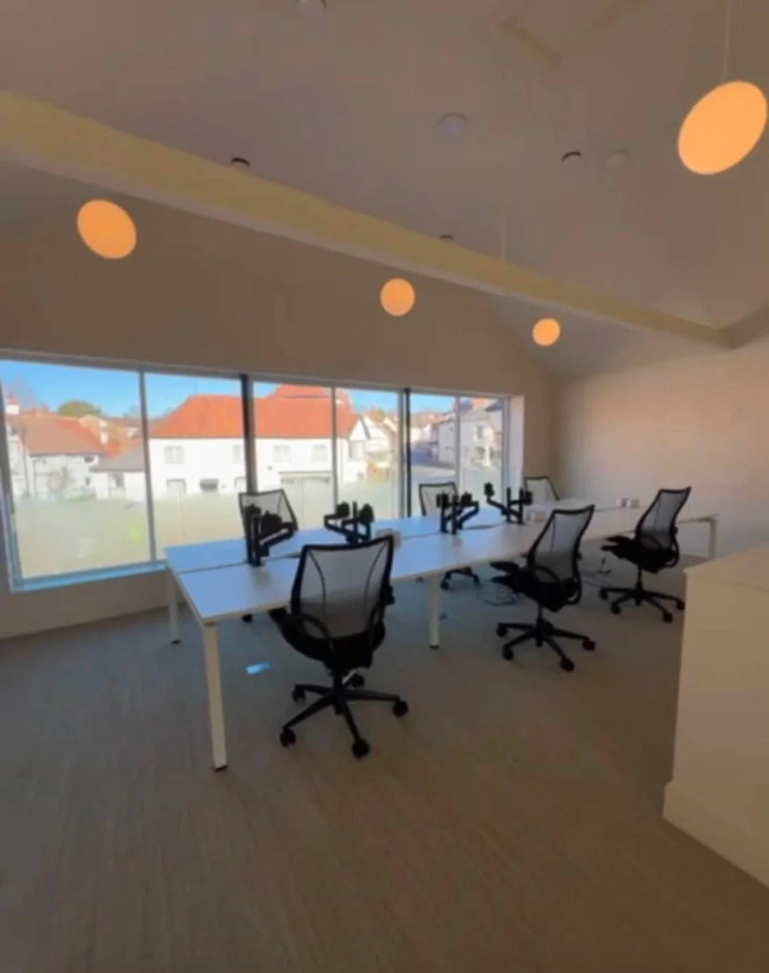 White desks and mesh chairs beside the broad window overlooking Whitchurch.
